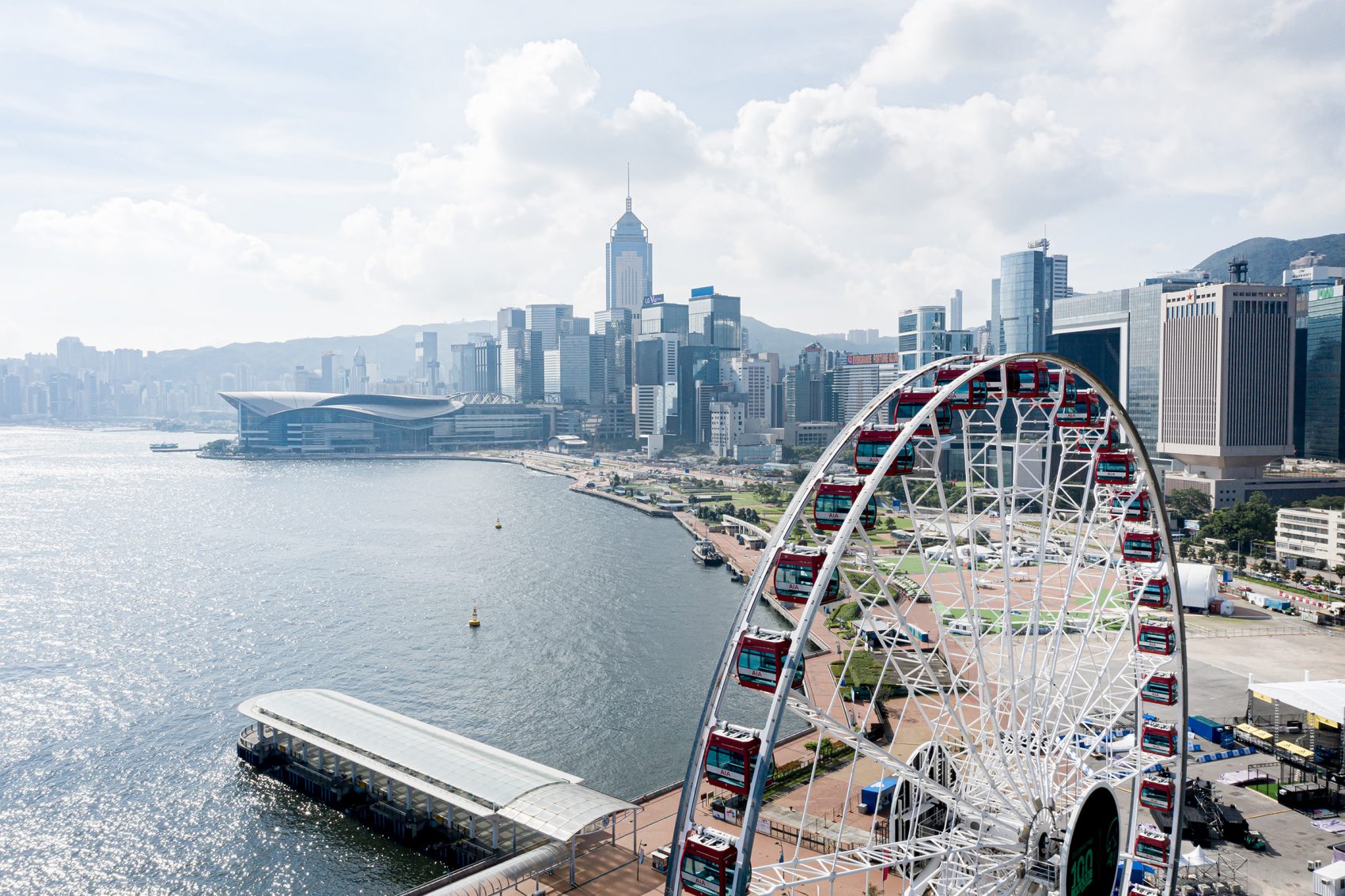 A bird’s eye view of the AIA Observation Wheel at the Central Harbourfront during daytime with a view of Victoria Harbour and iconic skyscrapers in Hong Kong.
