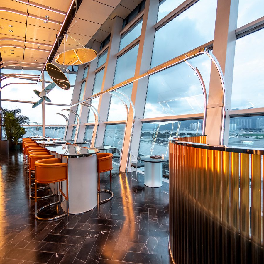 An interior view of Intervals Sky Bar & Restaurant at the Hong Kong International Airport, with a view of the runway during daytime.
