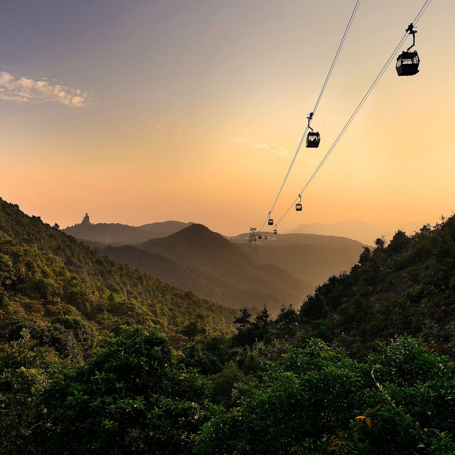 A drone shot of the Ngong Ping 360 cable car over the hills in Lantau Island during sunset. 