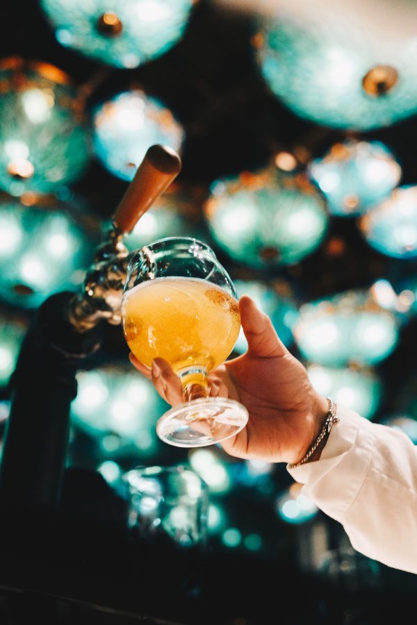 Person holding up a cocktail with a view of Dragonfly bar’s lights in Hong Kong.