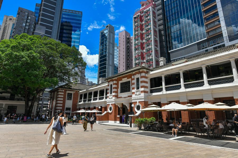 Woman walking through Tai Kwun courtyard in Hong Kong.