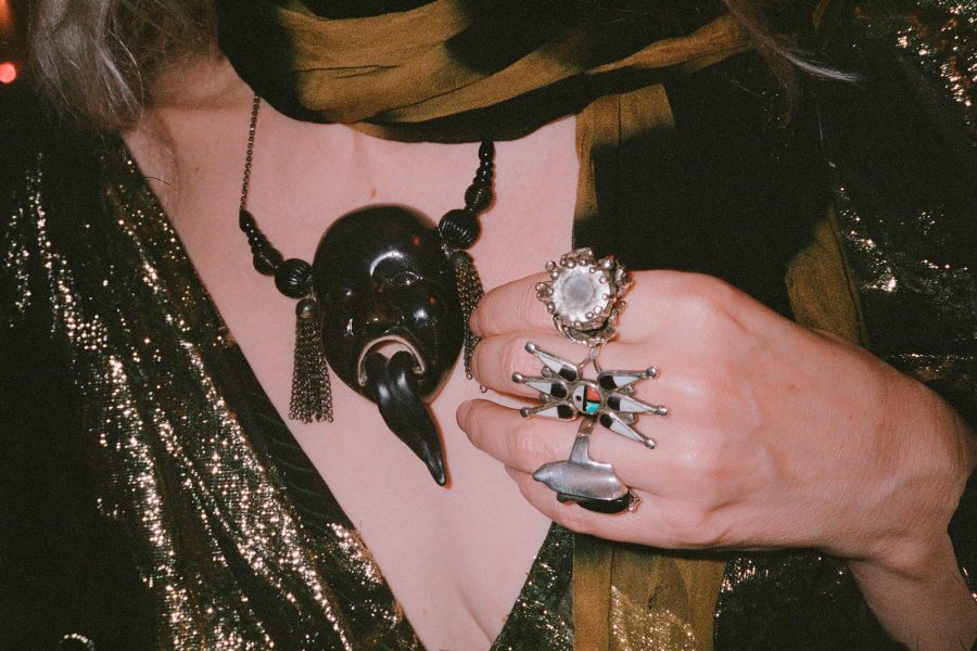 exterior of FineprintKayode Ojo’s Black Tongue New Year’s Eve (New York), a photograph of a stylish woman with her hand over her chest. She wears a necklace with a large pendant depicting a face with a tongue sticking out. 