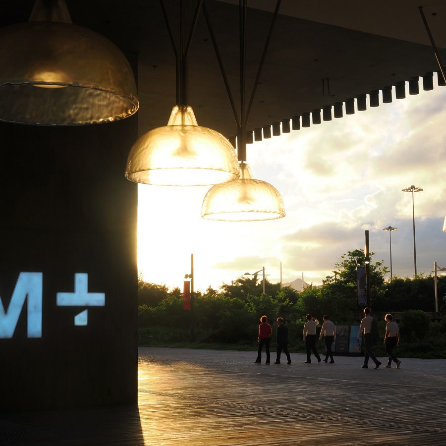 A group of people outside M+ Hong Kong in the late afternoon. 