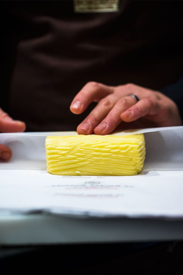 A person rolling a textured slab of butter in paper. 