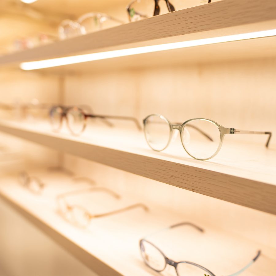 Rows of glasses lined up on white illuminated shelves.  