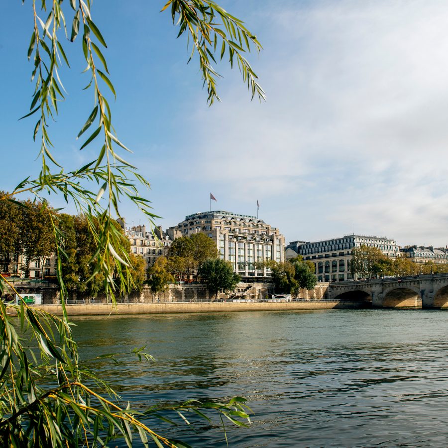 A view of the exterior of Cheval Blanc Paris, seen from a distance across a lake during daytime.