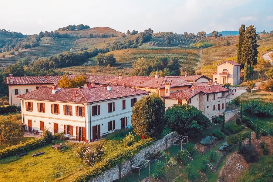 A bird’s eye view of the exterior of Oasi di Galbusera Bianca in the daytime surrounded by hills and vineyards in Curone Valley, Brianza near Milan.  