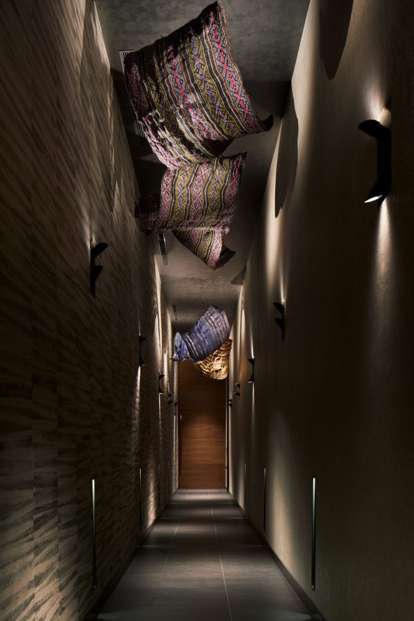 An interior view of a corridor at HOSHINOYA Guguan hotel in Taichung City, Taiwan, with traditional weaved cloths hanging overhead.