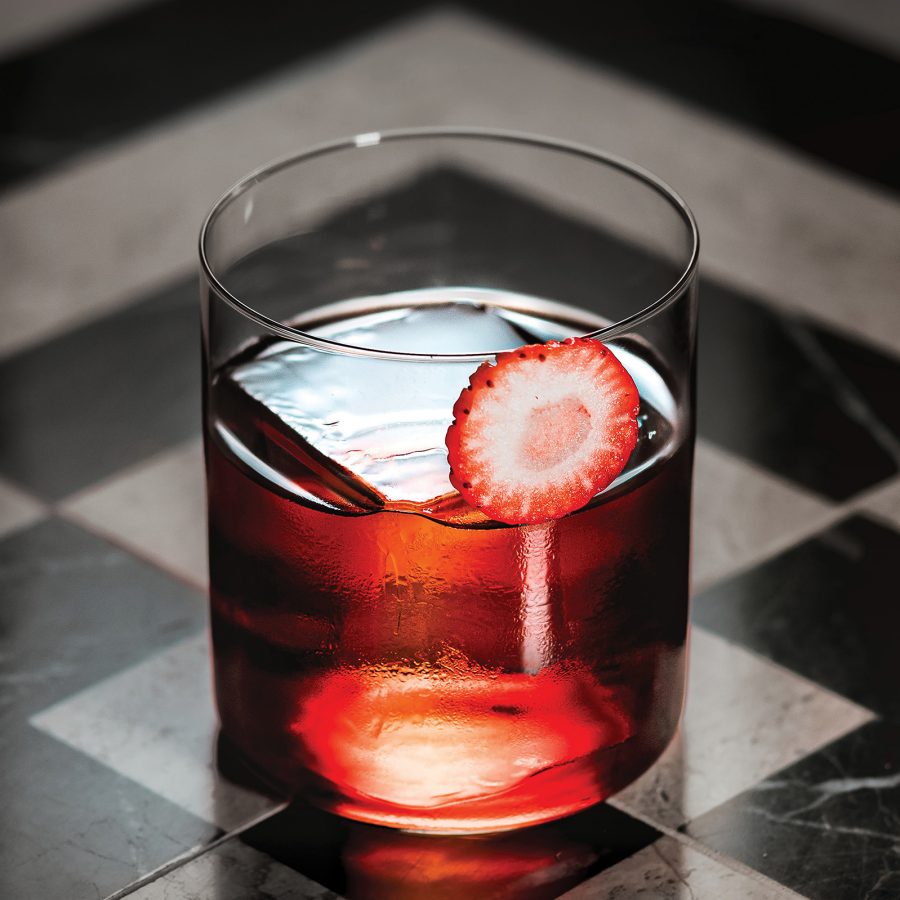 A closeup of a strawberry cocktail with a block of ice in a whisky glass, served at Jin Bo Law in Kai Tak, Hong Kong