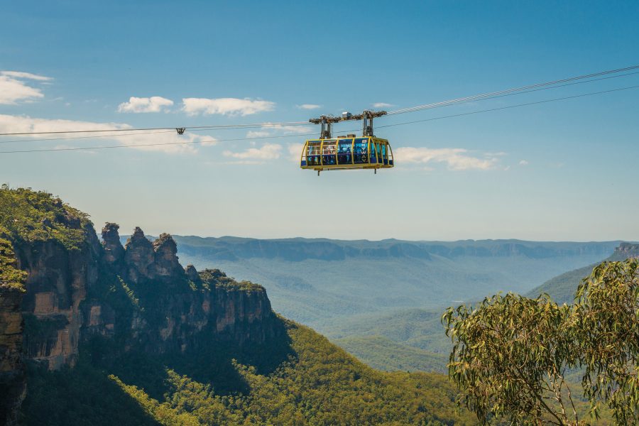 Visitors inside a cable car at the Blue Mountains National Park in Australia, with a view of the mountains and forest below.