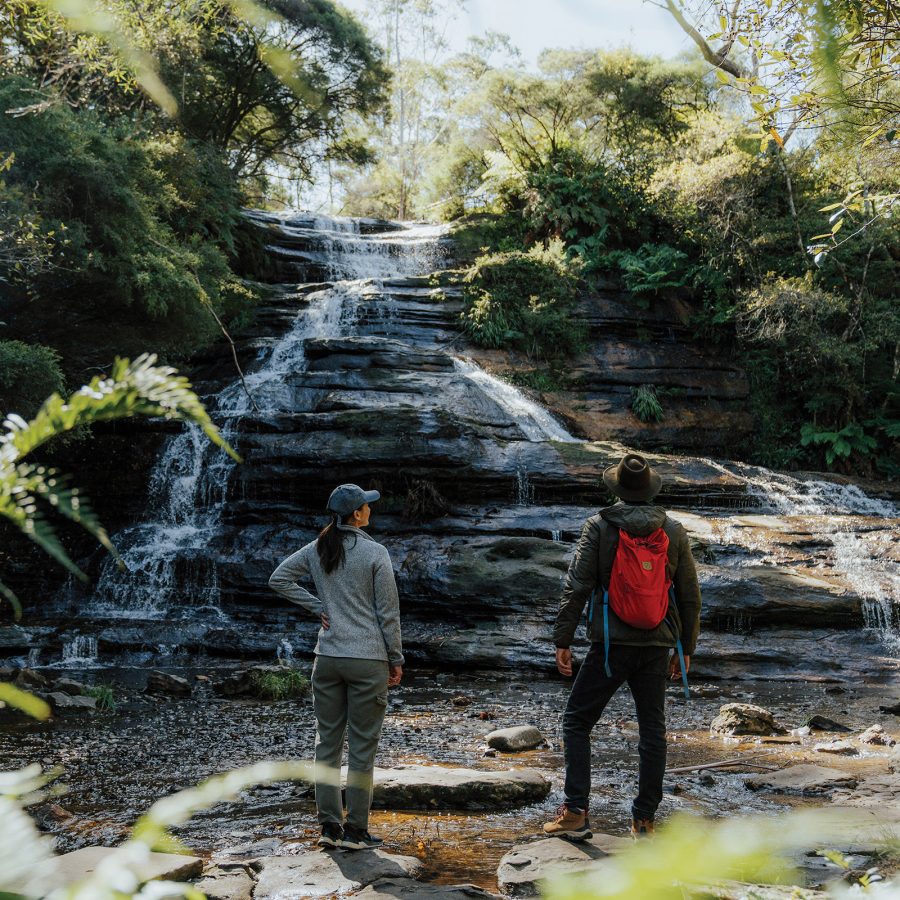 Two people standing in front of Katoomba Falls at the Blue Mountains National Park in Australia.