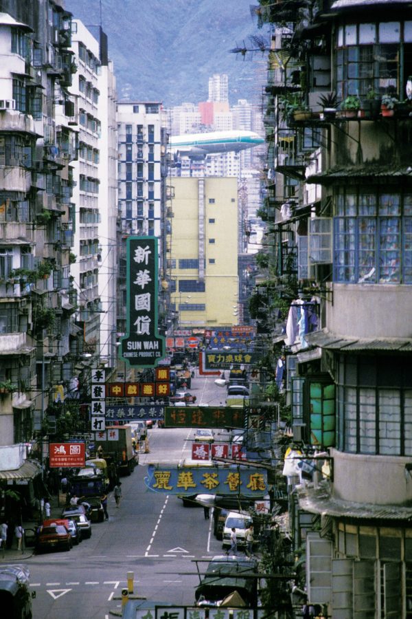 An image of a Cathay Pacific aircraft with classic green livery flying over old Kwun Chung area in Kowloon on the way to Kai Tak airport in Hong Kong.