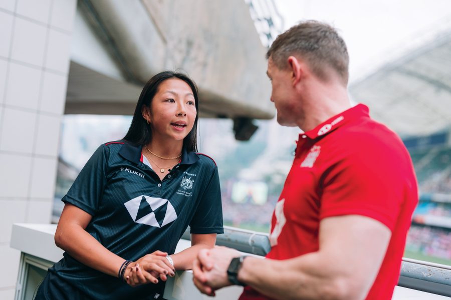 A woman and man wearing HSBC rugby shirts inside Hong Kong stadium.