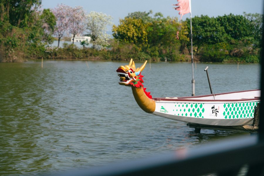 A dragon boat sailing along with trees in the background. 