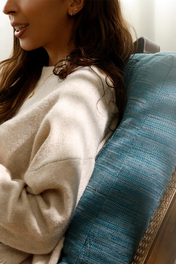 A person lies back on Cathay’s upcycled floor cushion, which can also be used for lounging on the sofa.