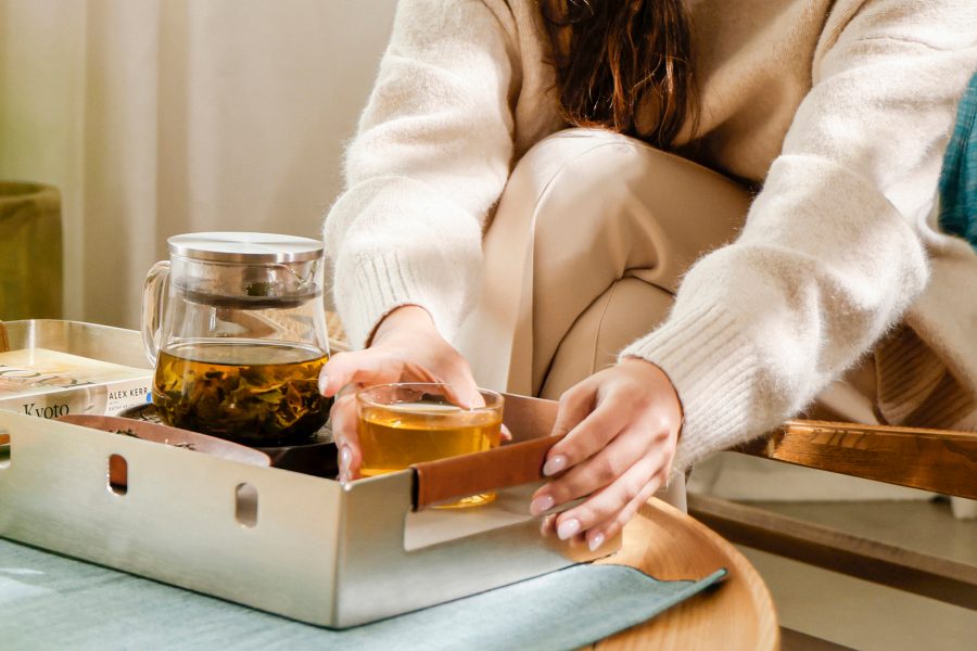 A person reaches for a cup of tea resting on top of Cathay’s upcycled tray. 