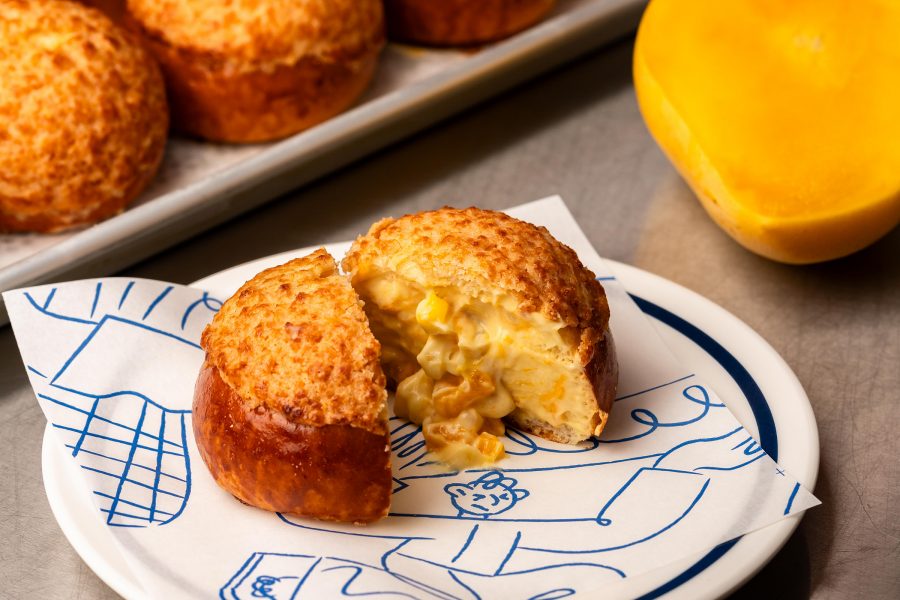 A plate with a mango sago bolo bao cut in half along with a tray of more of those buns at Bakehouse, Hong Kong. 