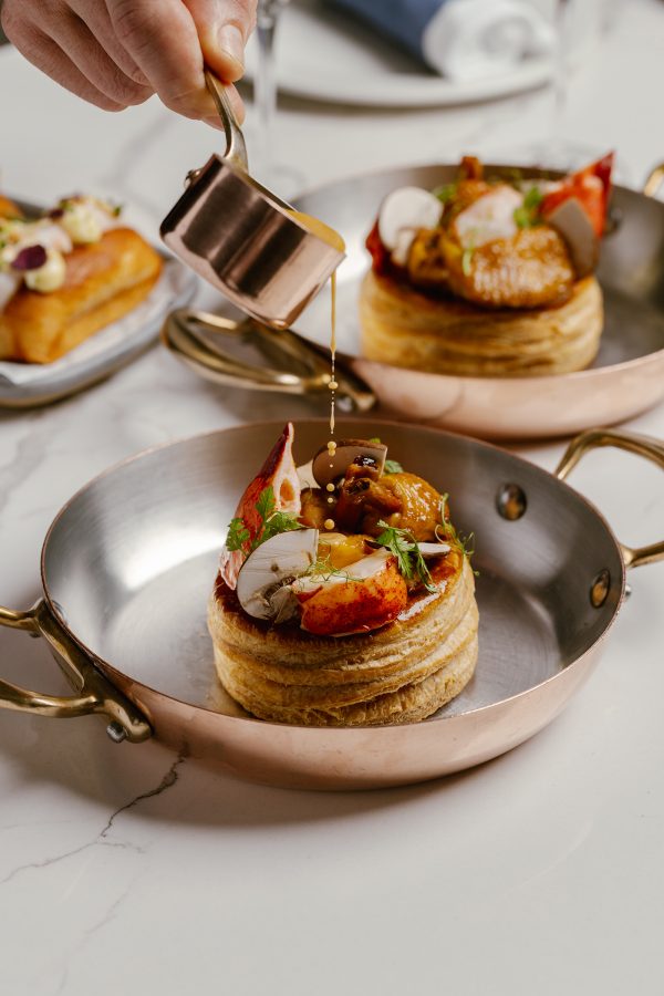 A hand pouring sauce onto a vol au vent at Lala in Hong Kong.
