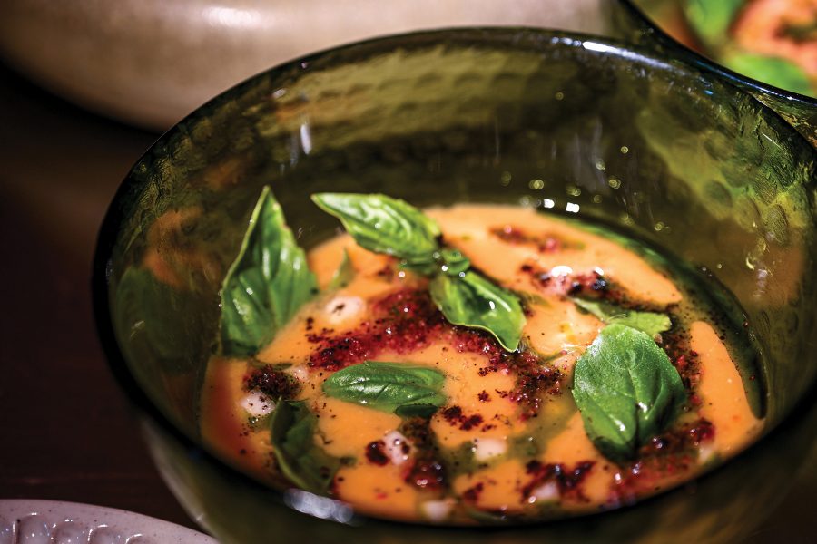 Close up view of a bowl of soup topped with basil leaves