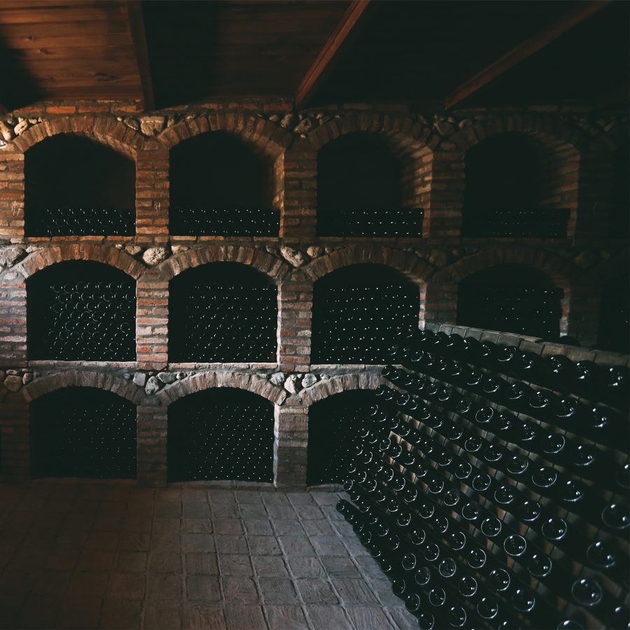 Inside a dark wood and brick cellar, dozens of rows of wine bottles are stacked on top of one another, at Orgo winery in Kakheti, Georgia.