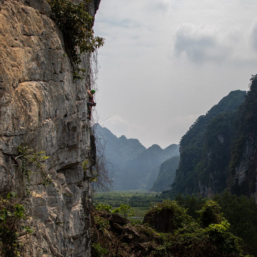 A view of a person rock climbing on a cliff edge at Huu Lung climbing cliff during daytime.