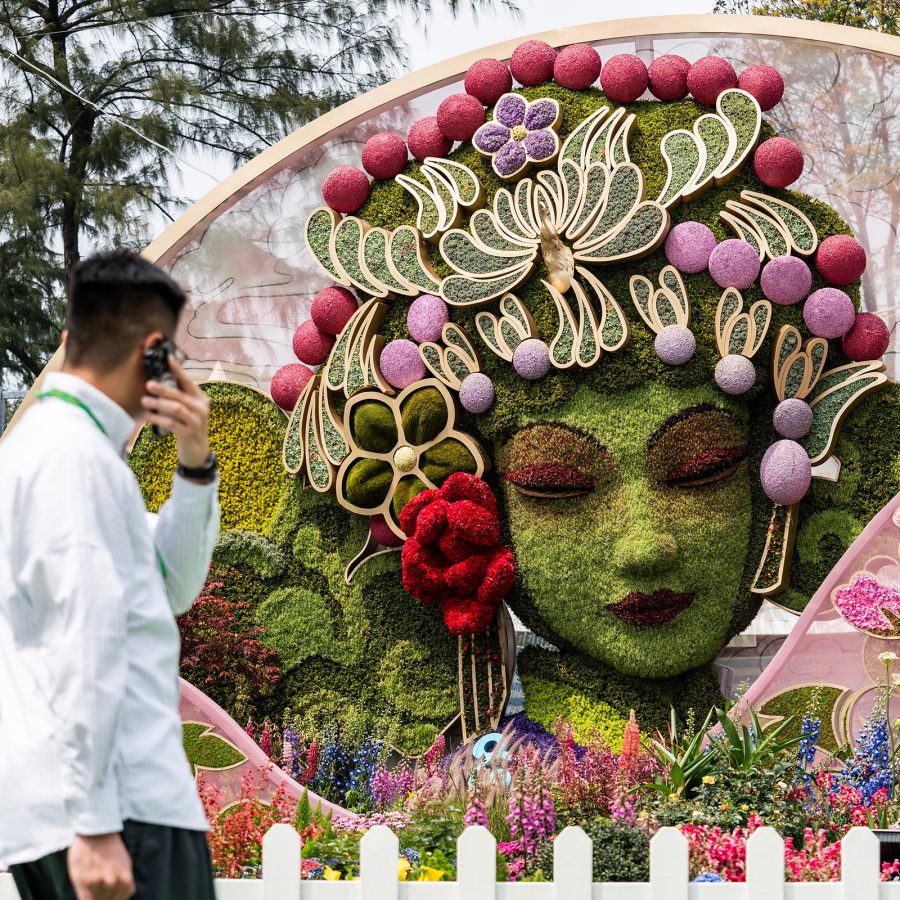 Attendee looks at a floral sculpture installation of a woman at the Hong Kong Flower Show.