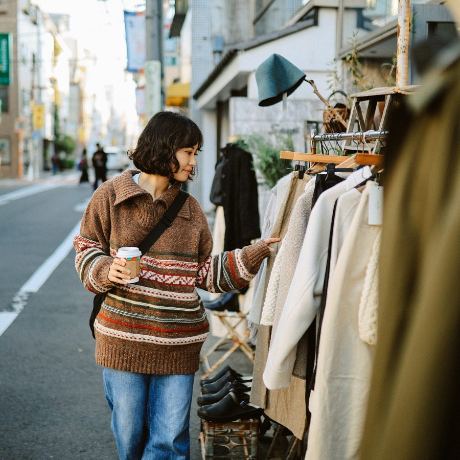 A woman browsing a rack of coats on the street outside New York Joe, Tokyo.