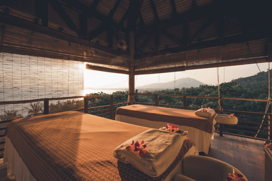 A wellness treatment room with two massage tables at Kamalaya, Koh Samui, with a view of the greenery outside in the afternoon. 