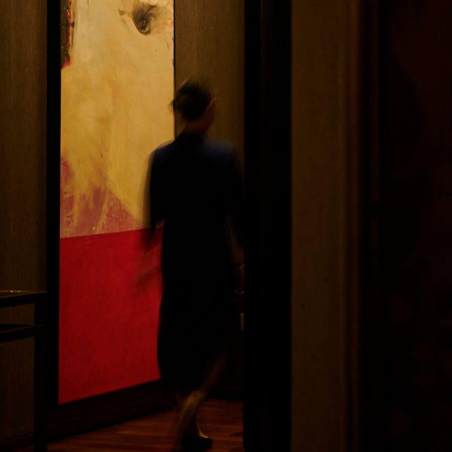 A waiter walking by a large painting in Jiang by Chef Fei.  