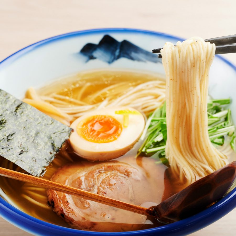 Close up view of Afuri’s yuzu salt chicken ramen with chopsticks lifting up a helping of noodles. 