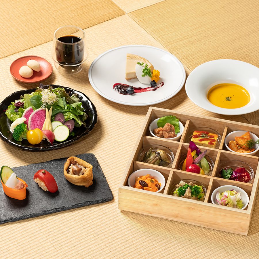 Arrangement of Ain Soph’s vegan dishes including soup and a box with multiple small plates. 