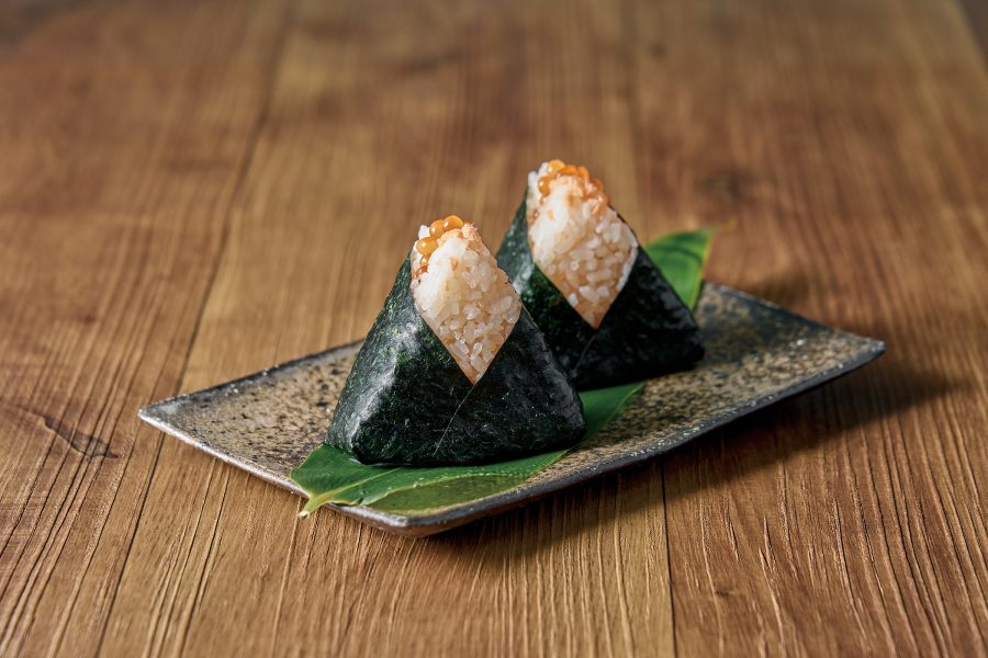 Close up on two triangular rice balls tightly wrapped in seaweed at Honnoriya. 