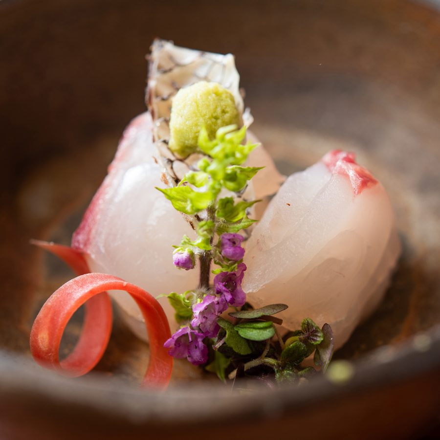 Close up on two pieces of nigiri plated on a brown bowl with flowers.
