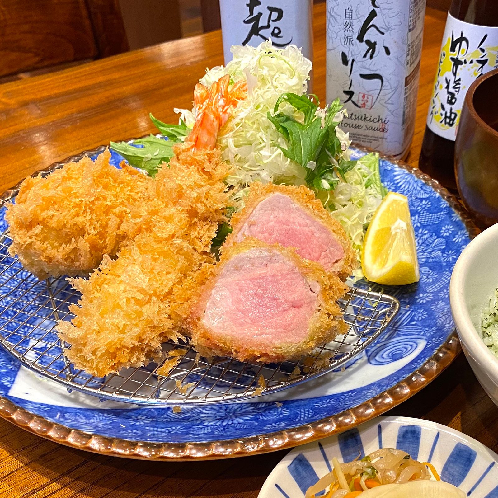 Close up on Katsukichi’s tonkatsu pork and prawns alongside side dishes.