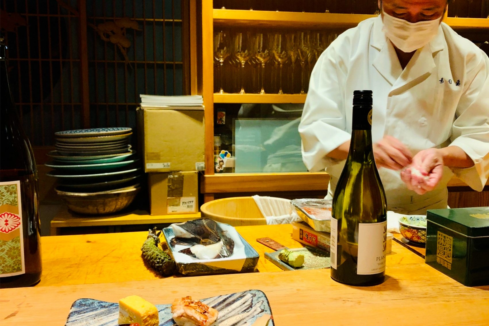 A sushi chef plates food at a counter in Sushi Yuu.