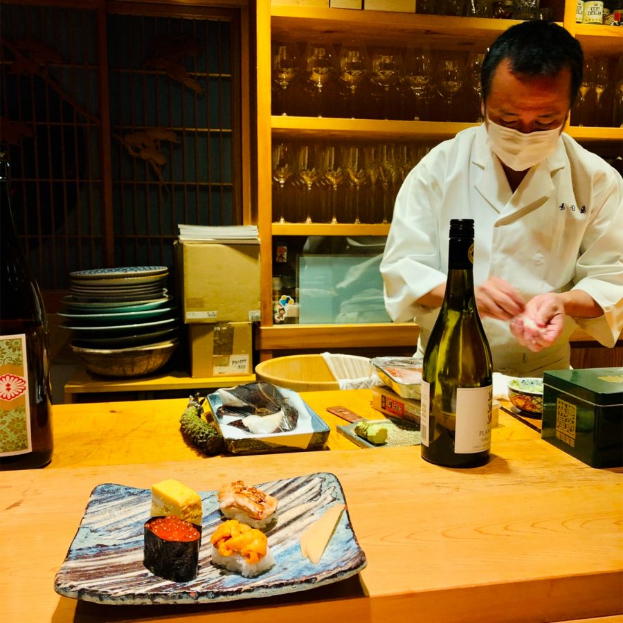 A sushi chef plates food at a counter in Sushi Yuu.