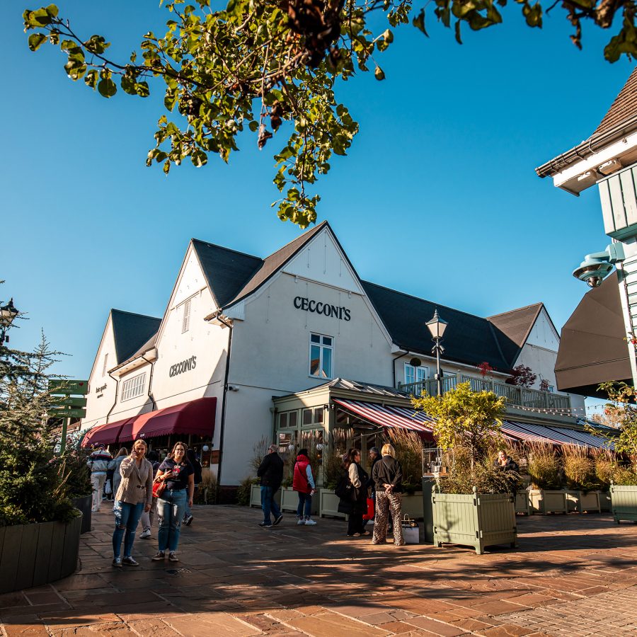 People mill about outside a restaurant labelled Cecconi’s at Bicester Village in the daytime. 