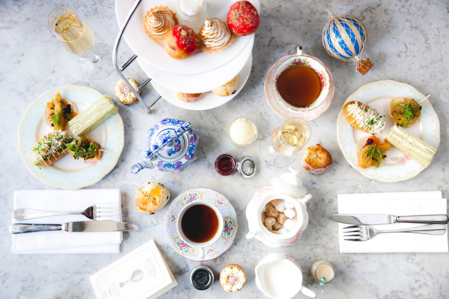 From above, an afternoon tea set is spread out across a marbled table, featuring small bites and tea. 