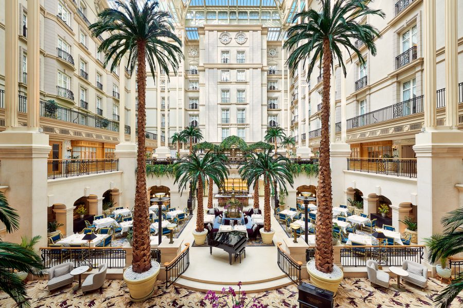 Palm trees line a spacious lobby inside The Landmark London. 