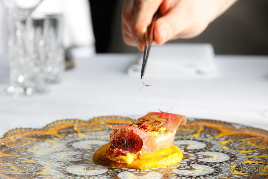 Chef delicately plating a dish at the Manoir de Lébioles in Belgium.
