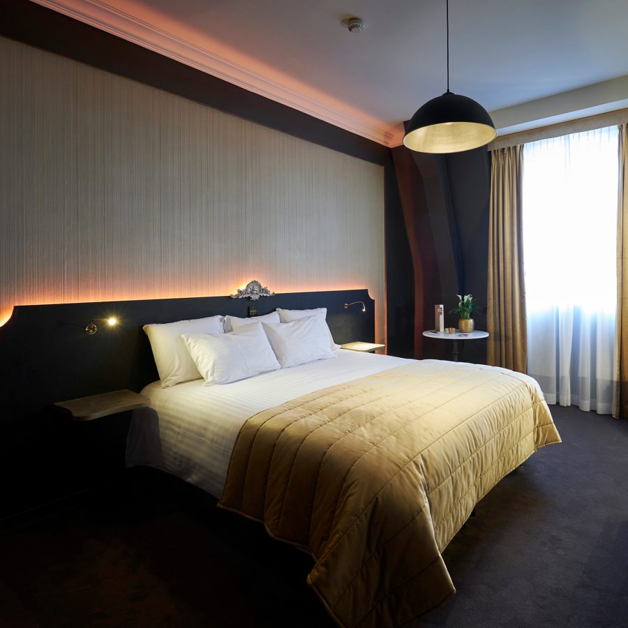 Dark interiors and a muted gold bed in a hotel room at Château de Namur.