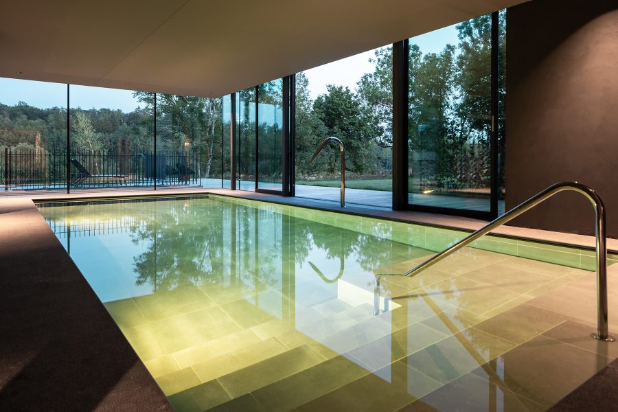 A mint-green swimming pool at the Château de Vignée with floor to ceiling windows. 