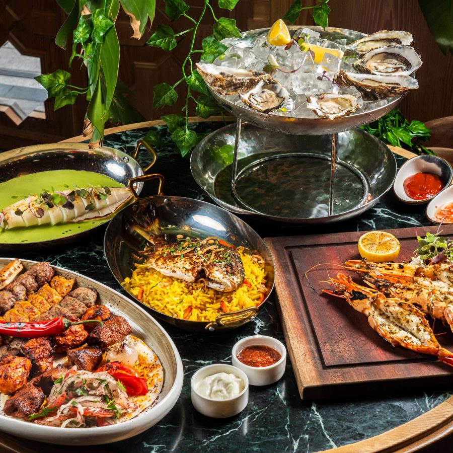 A spread of various dishes on the dining table, featuring a platter of halal meats, grilled seafood and fresh oysters on ice served at Lebanese restaurant Maison Du Mezze, Hong Kong.