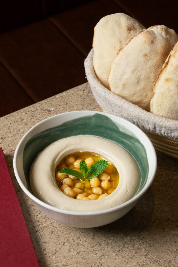 A bowl of homemade chickpea hummus next to a basket of freshly baked pita bread served at Lebanese restaurant Sumac, Hong Kong.