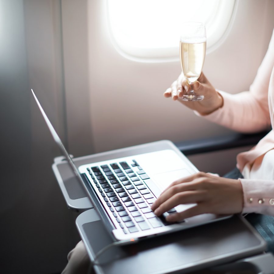 A passenger on their laptop while enjoying a glass of champagne on board a Cathay Pacific flight.
