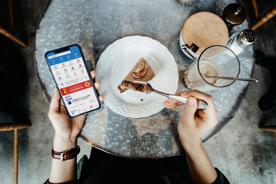A diner looks down at a stocks app as they eat a cake. 