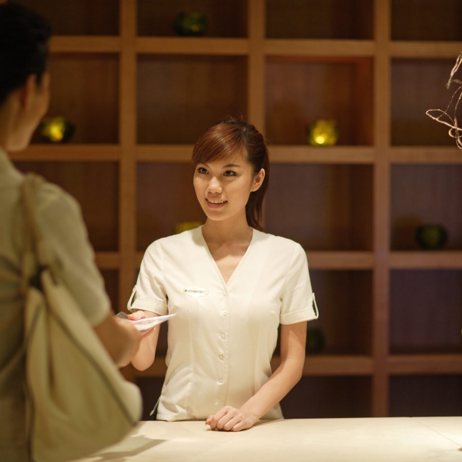 A customer hands a staff member payment for a spa and salon service in China. 