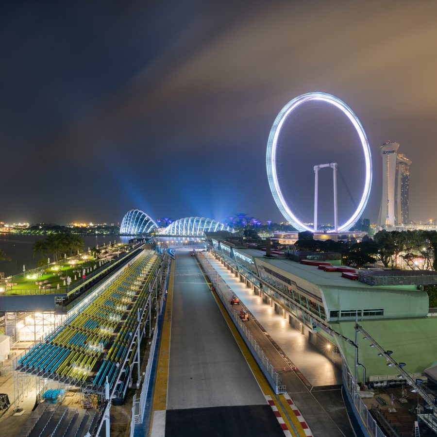 Street view of the Marina Bay Street Circuit with an illuminated Ferris wheel in the background in Singapore.