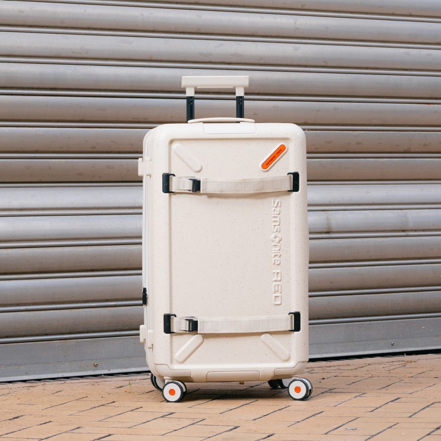 The ivory Samsonite TOIIS XP Trunk placed in front of a steel garage door.