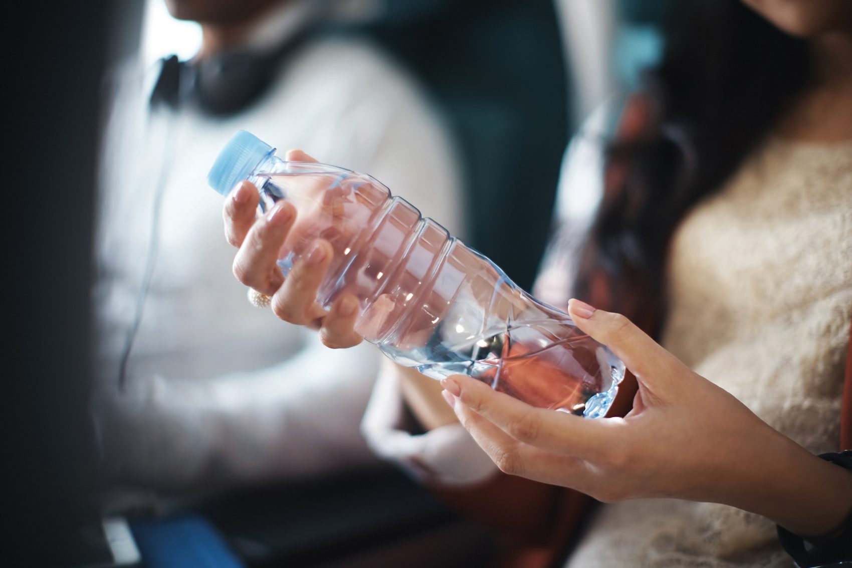 A seated woman holding a plastic bottle of water.